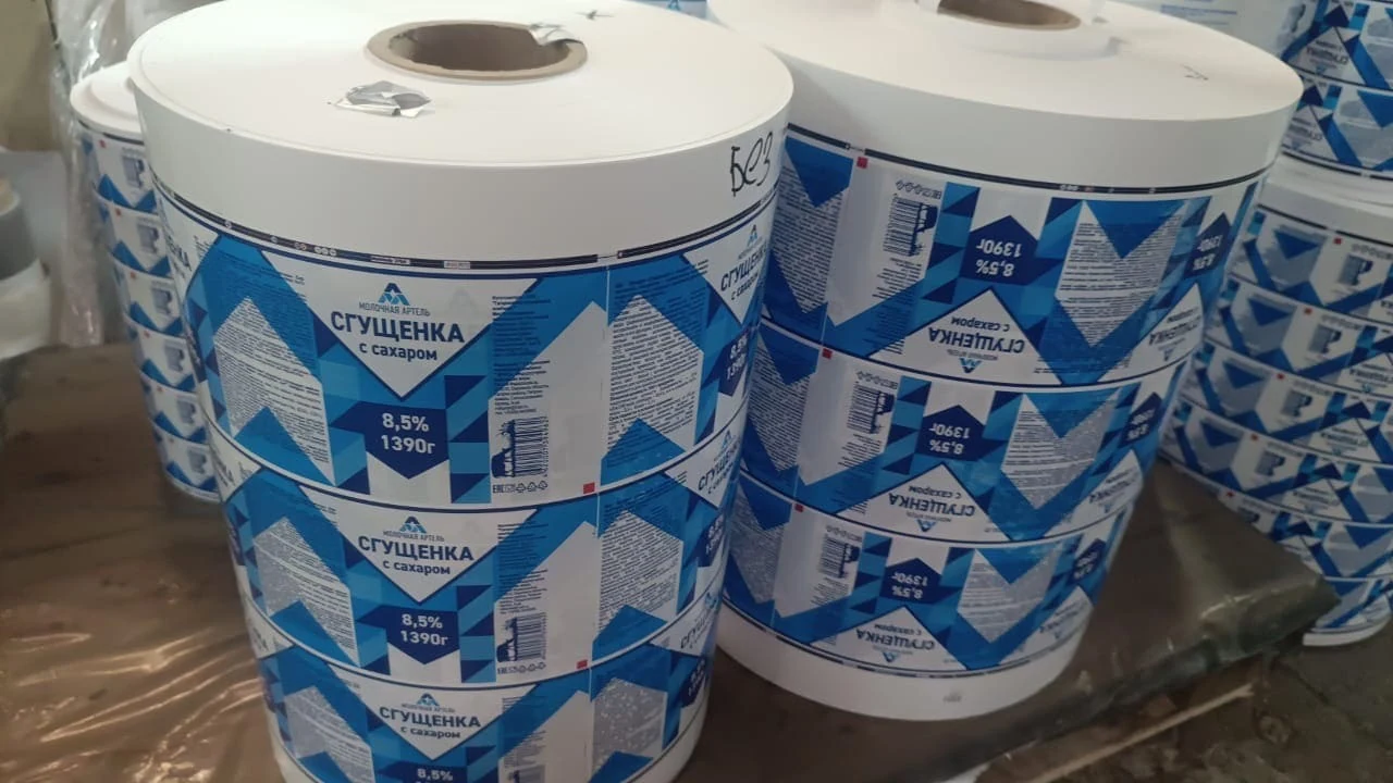 Этикетки для молочной продукции: несколько крупных рулонов с сине-белыми этикетками для сгущённого молока, составом и штрихкодом